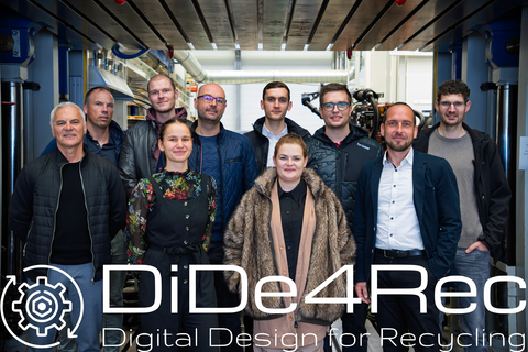 Ten people (eight men, two women) stand in front of a hydraulic press and smile at the camera. The DiDe4Rec logo appears on the photo.