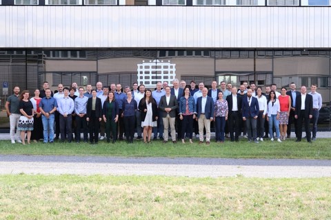 Group photo of about 50 people smiling and looking at the camera. They are standing outdoors in front of a building, which is visible in the background.