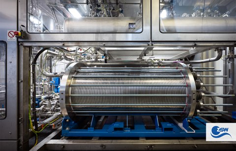 A metal, ribbed surface surrounded by rods and embedded in a metal machine.