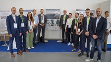 Am Stand des TRR/SFB 402: Personen stehen links und rechts vor einem Plakat und schauen in die Kamera. 