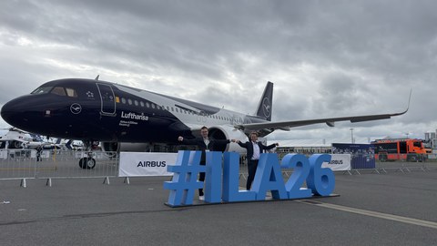 Zwei Männer stehen vor einem Lufthansaflugzeug. Vor ihnen befindet sich eine "ILA"-3D-Lettering-Installation.