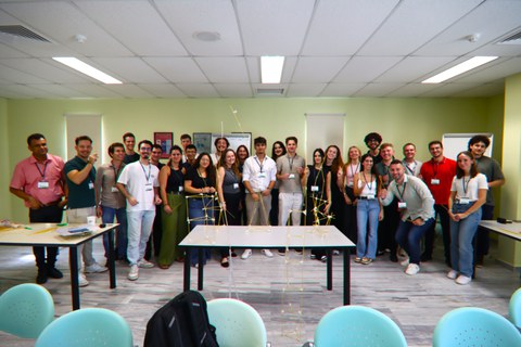 Group photo of all students. In front of them are the spaghetti towers on a table.