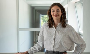 A woman looks into the camera and smiles.