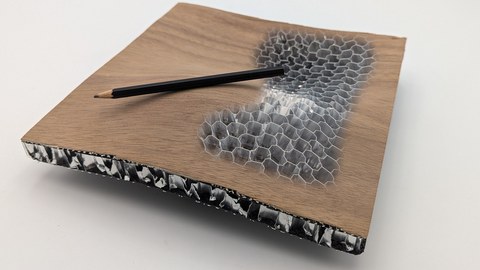 Das Bild zeigt ein doppelt gekrümmtes Formteil in Sandwichdwichbauweise mit Decklagen aus technischen Furnier und einer Kernlage aus dem innovativen, formbaren Wabenkern. Die Struktur des Wabenkerns ist offen gelegt und sichtbar.
