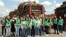 Gruppenfoto bei Kronospan vor Holzstapel