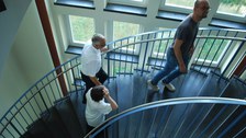 Drei Personen gehen eine Treppe hinauf.