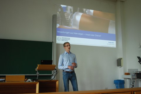 Vortragender Ludwig Schmidtchen mit Präsentation im Hintergrund.