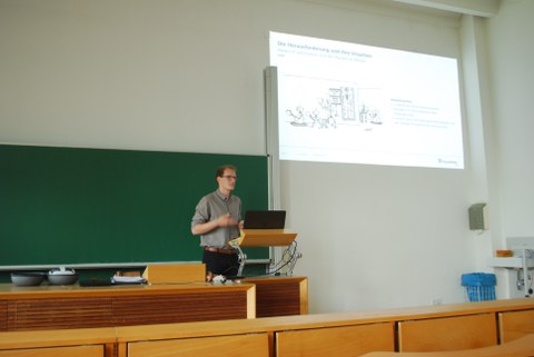 Vortragender Paul Weber mit Präsentation im Hintergrund.