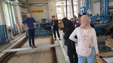Studierende im einer Industriehalle. Ein Mann steht auf einem Brett.