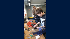 2 Jungen bauen in einer Werkstatt ein Getriebemodell zusammen.