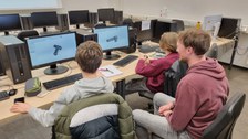 Ein Wissenschtler erklärt zwei Jungen ein Computerprogramm.