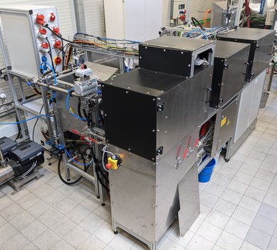 Pictur of a test rig with cables, tubes and three boxes with metal housings.