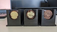Foto von drei Plastikteilen mit u-förmigen Querschnitten. Darin liegen Stangen aus brauner und weißer Schokolade.