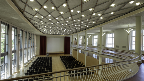 Foto eines Festsaals der TU Dresden, dem Dülfersaal mit Reihenbestuhlung und einer Bühne von oben.