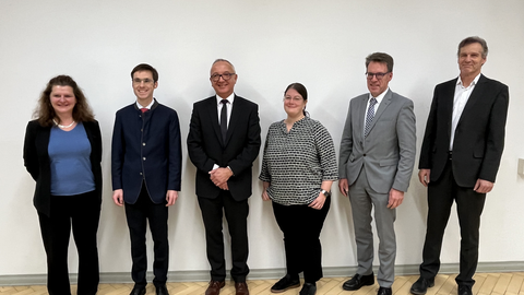 Gruppenbild mit 2 Frauen und 4 Männern in Businessoutfits.