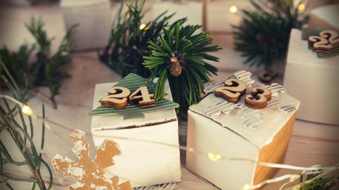 Das Foto zeigt eine Nahaufnahme eines geschmückten Weihnachtsbaumes mit einer brennenden Kerze und zwei Kugeln.
