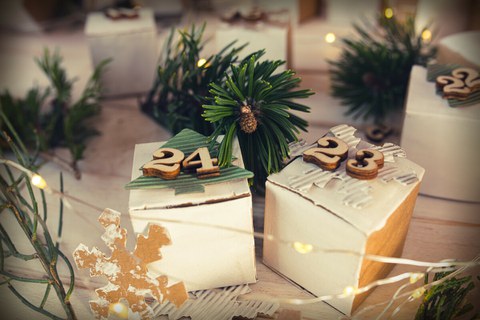 Das Foto zeigt eine Nahaufnahme eines geschmückten Weihnachtsbaumes mit einer brennenden Kerze und zwei Kugeln.