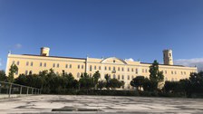 Gelbes Universitätsgebäude vor blauem Himmel.
