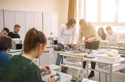 Auf dem Bild sind junge Menschen zu sehen, die sich in einem Kurs mit technischen Geräten beschäftigen