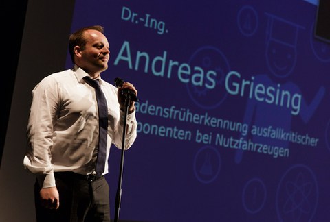 Der Gewinner des ersten Science-Slams der Fakultät Maschinenwesen, Dr. Andreas Griesing, auf der dunkelblauen Bühne des Boulevardtheater Dresden. Gleich spricht er in das Mikrophon, das vor ihm steht und beginnt seinen dreiminütigen Auftritt.