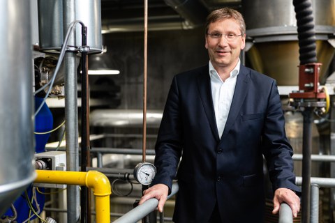 Foto von Professor Michael Beckmann vor dem Hintergrund einer virtuellen Stadtlandschaft 