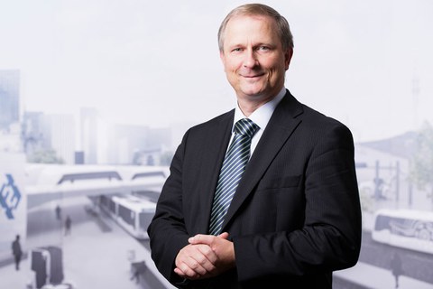 Foto von Professor Uwe Hampel vor dem Hintergrund einer virtuellen Stadtlandschaft