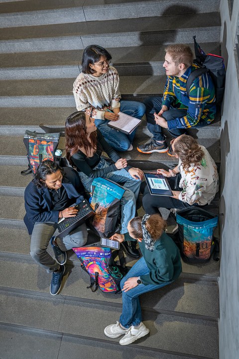 Auf dem Bild sind Studierende zu sehen, die auf dem Boden sitzen und lernen