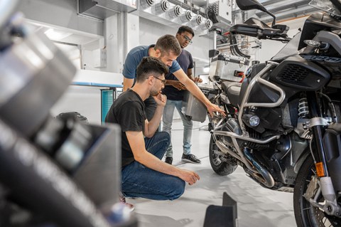 Auf dem Bild sind Studierende des Maschinenbaus an der TU Dresden zu sehen, die in einer Praxissituation in der Kraftfahrzeug- und Schienenfahrzeugtechnik fotografiert worden