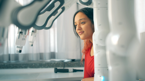 Mädchen schaut hinter Roboterarmen hervor.