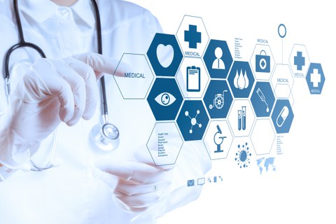 Ein Mensch weiß gekleidet und weißen Handschuhen mit Stetoskop um den Hals tippt auf einer digitalen Wand mit verschiedenen Icons.