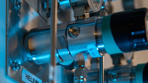 Blick auf ein Detail einer technischen Anlage, links im Bild ist an der Maschine der Begriff "Helium" zu lesen.
