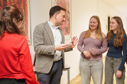 Vier Personen stehen vor Kunstwerke und diskutieren darüber.