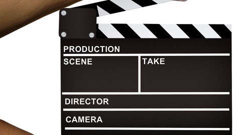 Auf dem Bild sieht man ein Filmklappe, die von sein Hände gehalten wird.