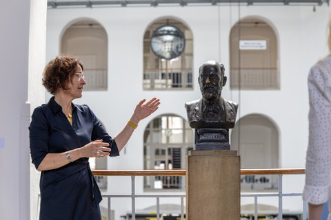 Foto von Frau Vincenz, Direktorin der Kustodie, mit der Büste von Hans Görges im Görges Bau
