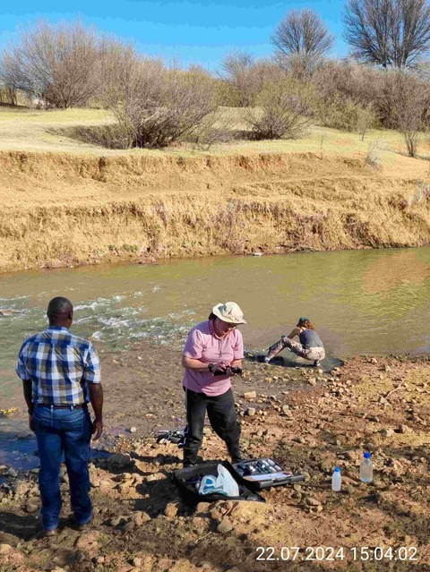 Zwei Personen entnehmen Wasserproben aus einem Fluss in Südafrika.