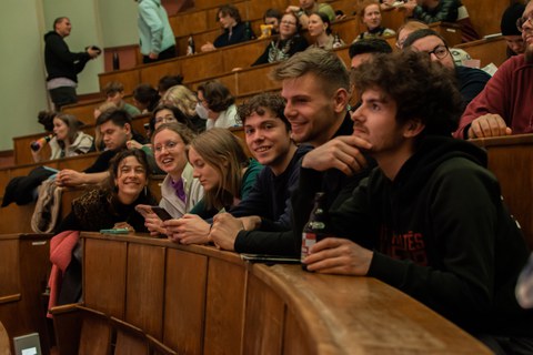 Lachende Studierende auf Hörsaalbänken.