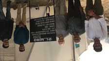 Fünf Männer stehen neben einem Schild vor einem Gewächshaus. Auf dem Schild sind Einzelheiten zu einem Projekt zu finden, darunter Name und Adresse des Landwirts sowie Informationen zum Projekt.