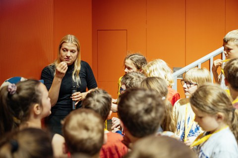 Referentin erklärt etwas, um sie herum stehen Kinder
