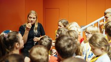 Referentin erklärt etwas, um sie herum stehen Kinder