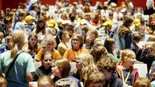 Viele Kinder sitzen in Stuhlreihen.