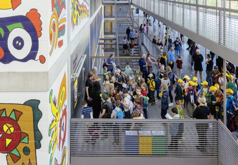 In einem Treppenhaus stehen viele Kinder vor einer Tür.