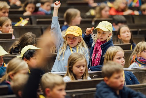 Kinder in den Sitzreihen des Hörsaals.