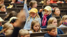 Kinder in den Sitzreihen des Hörsaals.