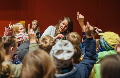 Nach der Vorlesung stehen einige Kinder bei der Referentin und stellen ihr Fragen. Dazu melden sie sich mit Handzeichen.