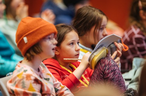 Die Kinder hören aufmerksam zu und machen sich Notizen.