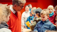 Der Dozent unterhält sich mit Kinder, die um ihn herumstehen.