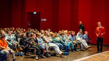 Viele Kinder sitzen in einem Saal.