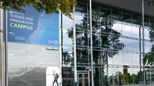 Glasfassade des Hörsaalzentrums mit reflektierenden Fenstern und blauem Banner 'Welcome to the Science and Innovation Campus'