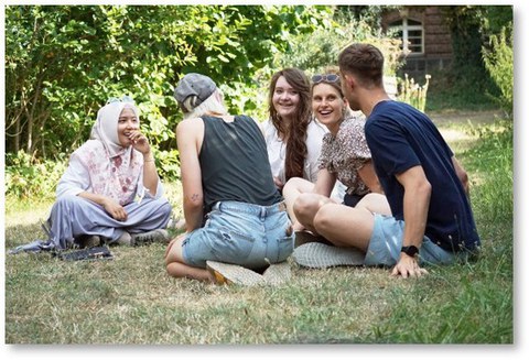 Studierende auf einer Wiese sitzend im Gespräch