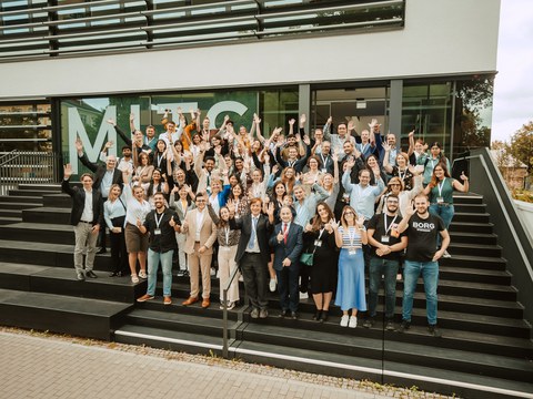 Gruppenbild von jubelnden Teilnehmern und Professoren des Graduiertenkollegs vor dem MITS Gebäude auf dem Campus der Medizinischen Fakultät der TU Dresden.